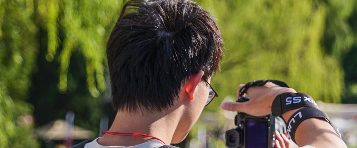 A photographer shooting with a Lumix mirrorless camera by a lake