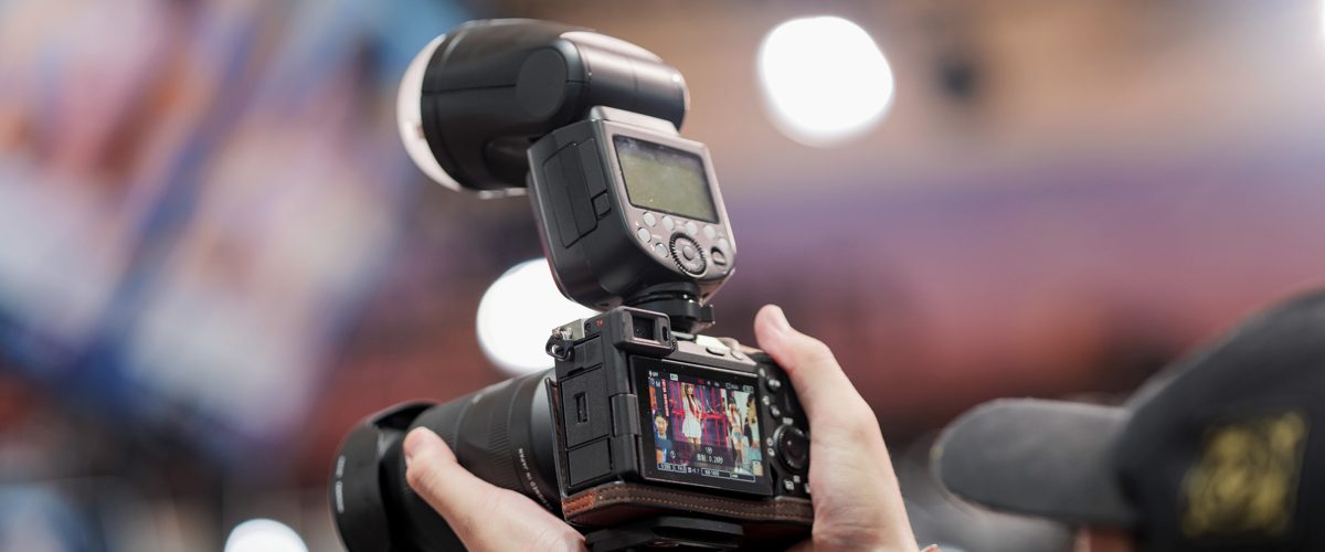Hands holding a Sony mirrorless camera with a flash, mid-shoot