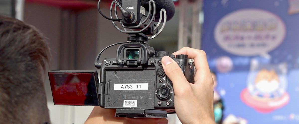 A Sony mirrorless camera with its screen flipped out, recording an event